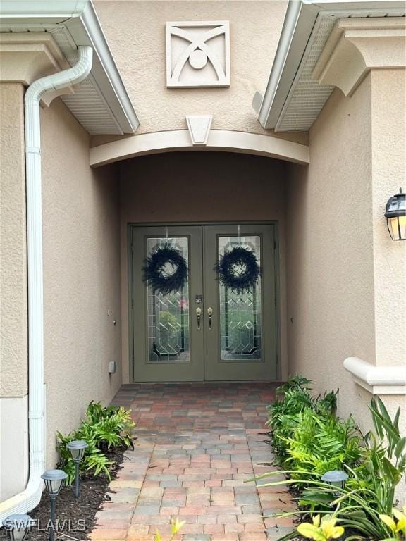 view of exterior entry featuring french doors and stucco siding