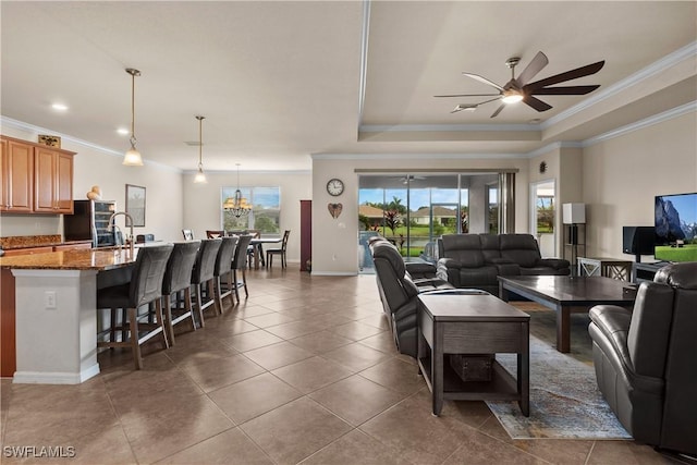 living area with dark tile patterned flooring, crown molding, and a tray ceiling