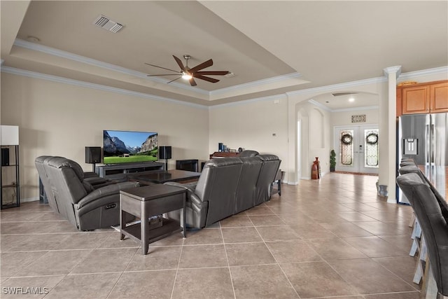 living area featuring arched walkways, french doors, a raised ceiling, and visible vents