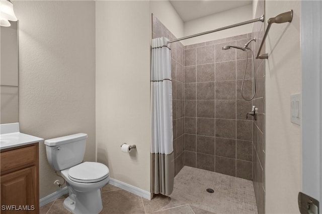 bathroom with toilet, tiled shower, tile patterned flooring, and vanity