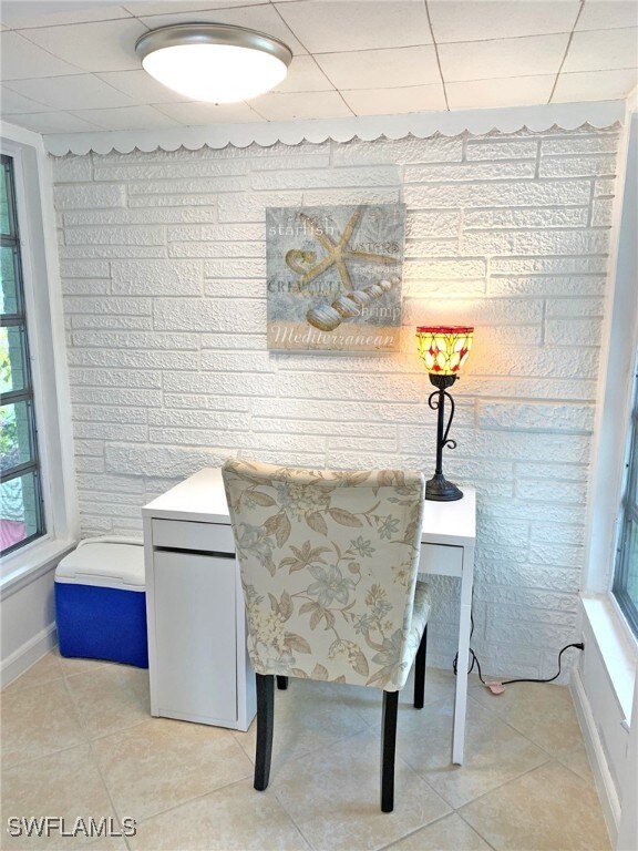 dining area with a drop ceiling, light tile patterned flooring, and baseboards