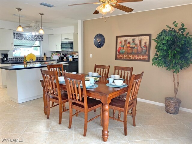 dining room featuring baseboards, visible vents, a ceiling fan, and light tile patterned flooring