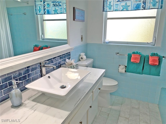 bathroom featuring a healthy amount of sunlight, a wainscoted wall, toilet, and a sink