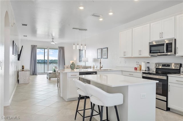 kitchen featuring light tile patterned floors, a peninsula, stainless steel appliances, light countertops, and a sink