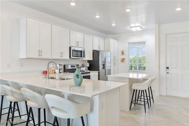 kitchen with stainless steel appliances, a breakfast bar, a peninsula, a kitchen island, and a sink