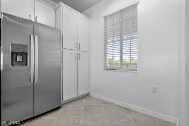 kitchen with white cabinets, stainless steel refrigerator with ice dispenser, baseboards, and light tile patterned floors