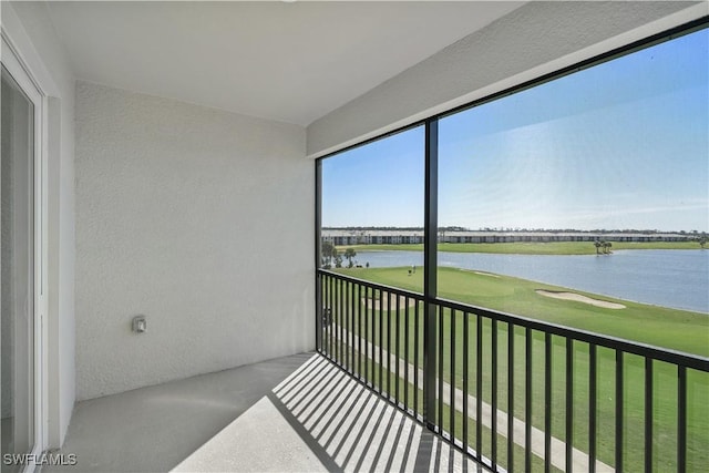 sunroom featuring view of golf course and a water view