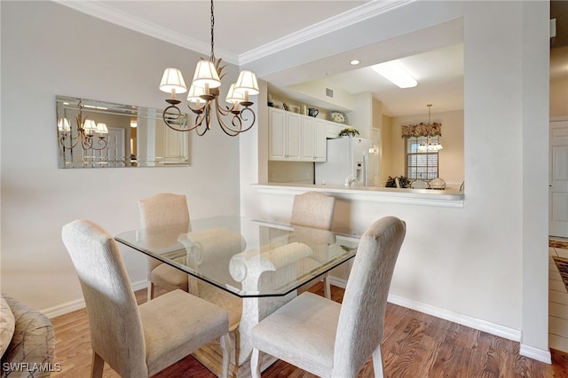 dining space with baseboards, ornamental molding, wood finished floors, and an inviting chandelier