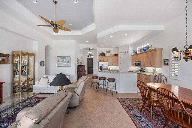 6574 Caldecott Dr, Naples, FL 34113 - living area with arched walkways, light tile patterned floors, recessed lighting, ceiling fan with notable chandelier, and a tray ceiling
