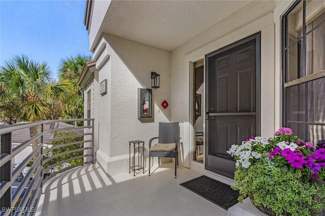 property entrance with a balcony and stucco siding