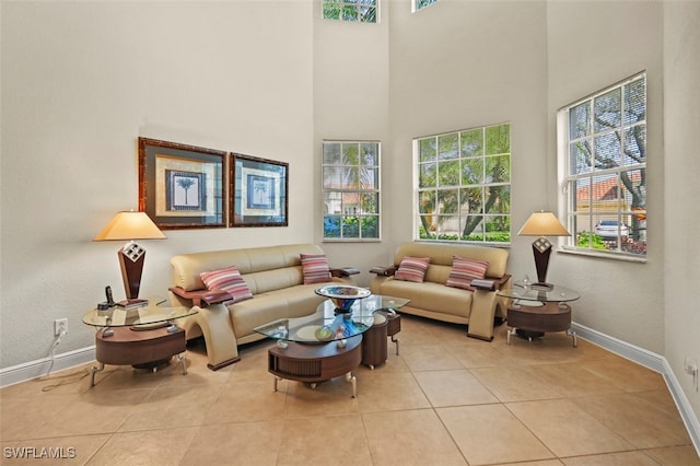 interior space with light tile patterned floors, a towering ceiling, and baseboards