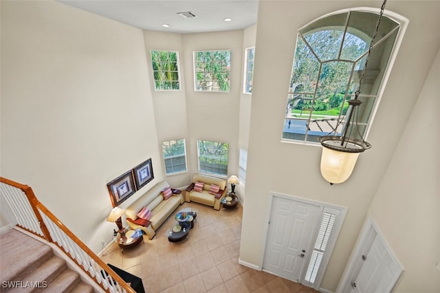 interior space with a towering ceiling, a healthy amount of sunlight, and stairway