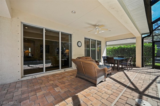 view of patio with ceiling fan, outdoor dining area, and a lanai