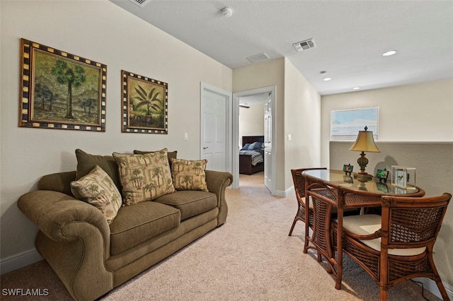 living area featuring visible vents, light carpet, and baseboards