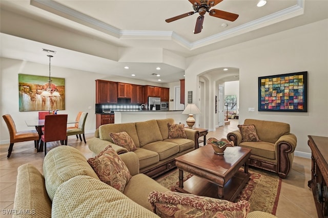 living room with arched walkways, a tray ceiling, and light tile patterned flooring