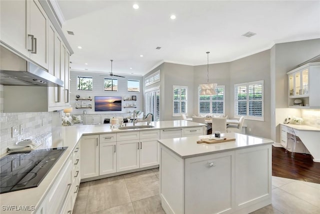 kitchen with light tile patterned floors, tasteful backsplash, a peninsula, black electric cooktop, and a sink