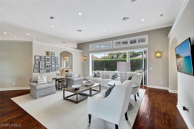 living room featuring arched walkways, visible vents, baseboards, hardwood / wood-style floors, and crown molding