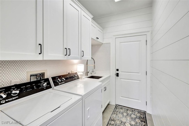 laundry room with cabinet space, wooden walls, a sink, and independent washer and dryer