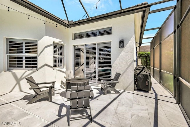 view of patio with area for grilling and a lanai