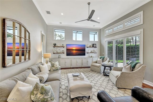 living room with ceiling fan, baseboards, visible vents, and crown molding