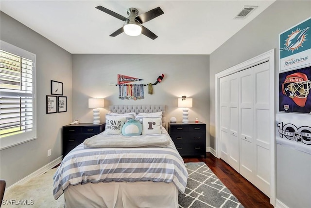 bedroom with a closet, visible vents, baseboards, and wood finished floors