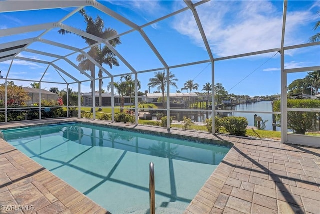 pool with glass enclosure, a patio area, and a water view