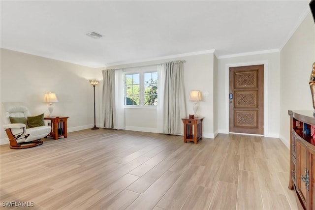 sitting room with light wood finished floors, visible vents, baseboards, and ornamental molding