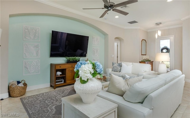 living area with arched walkways, visible vents, crown molding, and baseboards