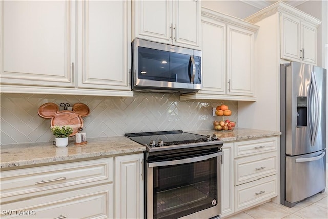 kitchen with tasteful backsplash, appliances with stainless steel finishes, white cabinets, light tile patterned flooring, and light stone countertops