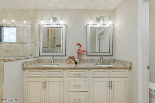 bathroom with double vanity, a sink, and tiled shower