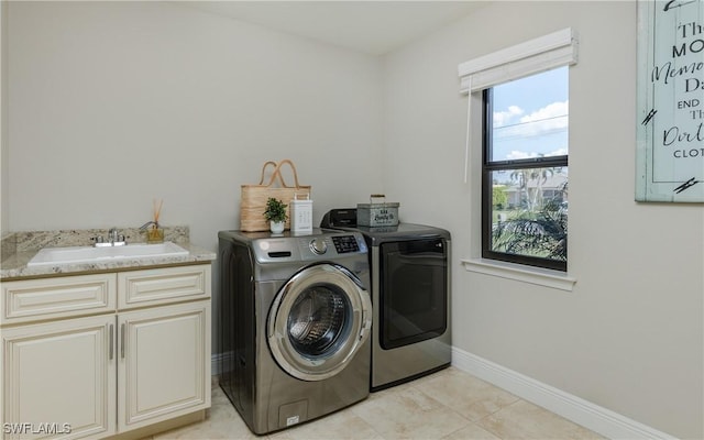 clothes washing area featuring light tile patterned floors, a sink, baseboards, independent washer and dryer, and cabinet space