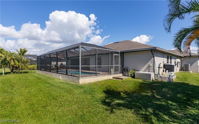 back of house with glass enclosure, central air condition unit, a yard, a fenced in pool, and stucco siding