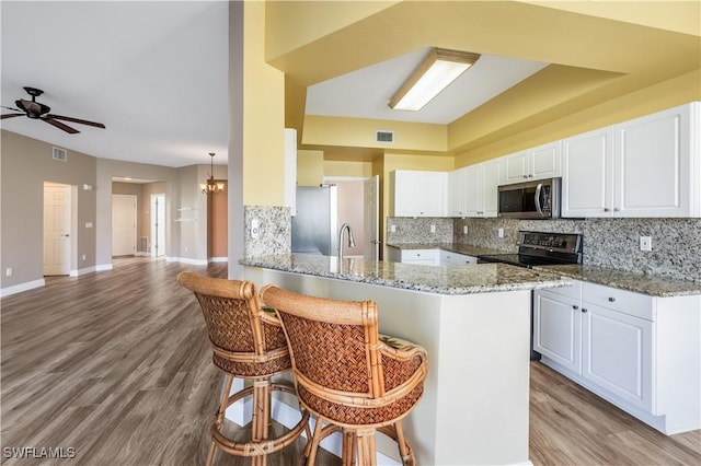 kitchen with appliances with stainless steel finishes, visible vents, a kitchen bar, and tasteful backsplash