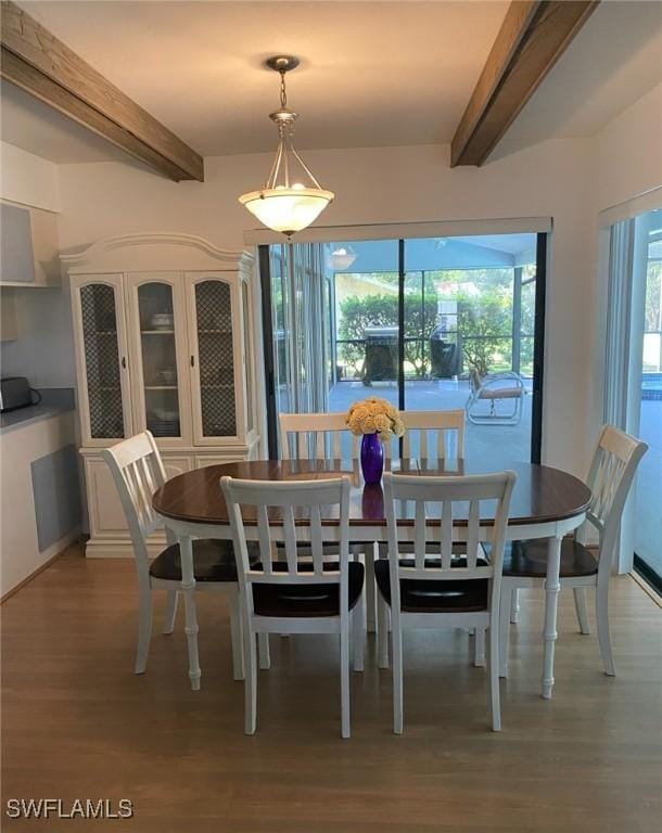 dining room with beamed ceiling, a healthy amount of sunlight, and light wood finished floors