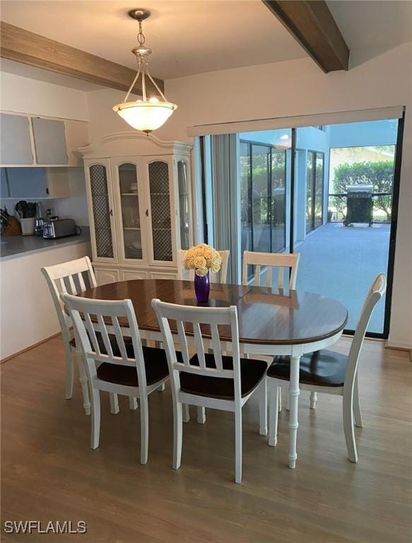 dining room with beam ceiling and wood finished floors