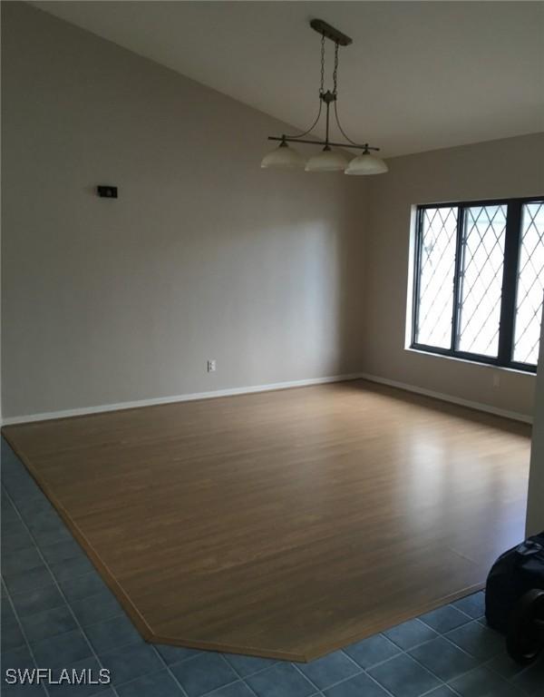 spare room featuring baseboards and dark wood finished floors