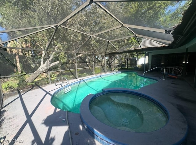 view of swimming pool featuring a patio area, glass enclosure, and a pool with connected hot tub