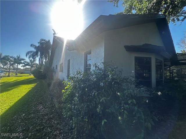 view of side of home featuring a yard and stucco siding