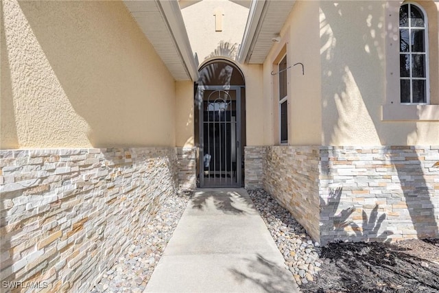 doorway to property with stone siding and stucco siding