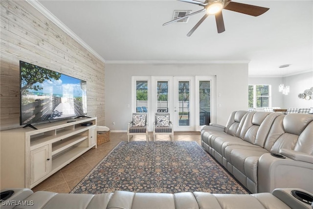 living room with light tile patterned floors, ceiling fan with notable chandelier, ornamental molding, and french doors