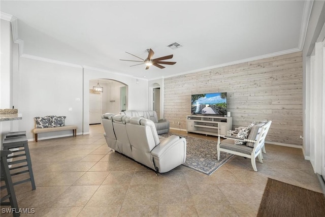 living room featuring light tile patterned floors, ceiling fan, arched walkways, and ornamental molding