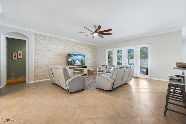 living area with an accent wall, french doors, crown molding, and baseboards