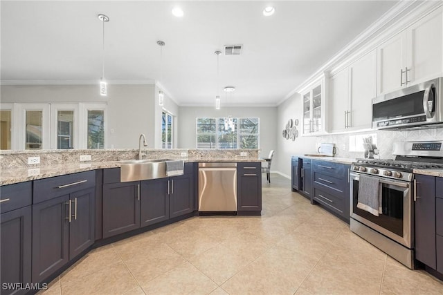 kitchen featuring hanging light fixtures, appliances with stainless steel finishes, a sink, and white cabinets