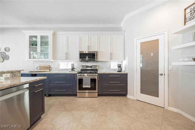 kitchen with light stone counters, stainless steel appliances, white cabinetry, ornamental molding, and decorative backsplash