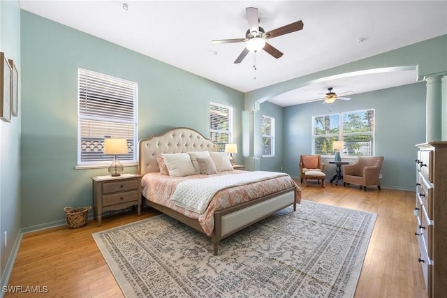 bedroom with light wood finished floors, ceiling fan, decorative columns, and baseboards