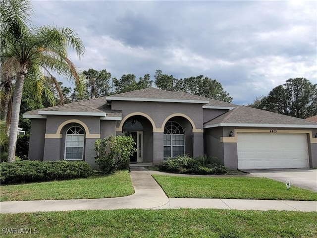 view of front of property with a front yard, driveway, an attached garage, and stucco siding