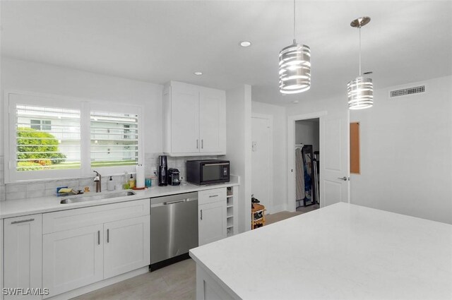 kitchen featuring black microwave, a sink, visible vents, light countertops, and stainless steel dishwasher