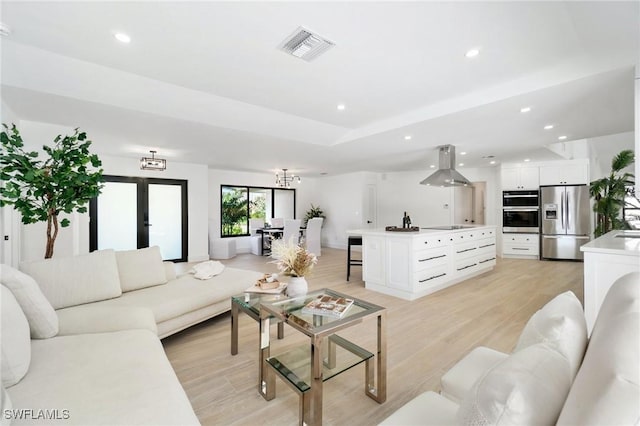 living area featuring a tray ceiling, recessed lighting, visible vents, and light wood-style floors