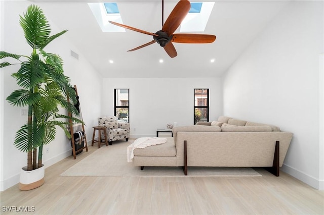 living room featuring high vaulted ceiling, light wood-style flooring, a skylight, visible vents, and a ceiling fan