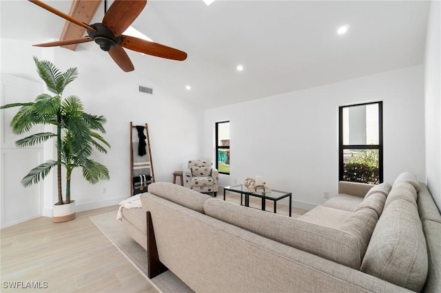 living area featuring light wood-style floors, visible vents, vaulted ceiling, and a wealth of natural light